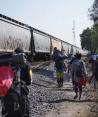 Migrantes caminan junto a un tren con dirección al norte, esperando poder subirse a él, en Huehuetoca, México, el viernes 12 de mayo de 2023.