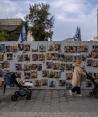 Ciudadanos caminan frente a vallas en Tel Aviv con pancartas de los rostros de las víctimas que secuestró Hamas, ayer.