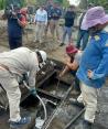 Trabajadores de Pemex y Protección Civil al limpiar una coladera, ayer.