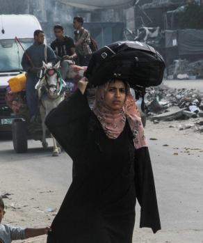 Mujeres y hombres, a pie o en transporte, cargan sus pocas pertenencias para escapar de Rafah, su último refugio.